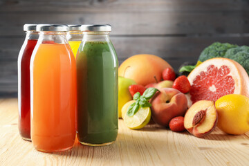 Tasty juices in glass bottles, fresh ingredients and basil on wooden table against brown background, closeup