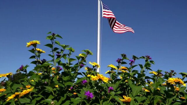 national banner affixed to pole standing beside blooming flora against sky backdrop