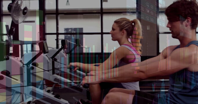 Rowing workout partners using rowing machines at modern gym, with wall fan and stock chart overlays