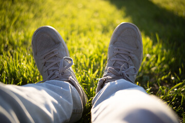 First-person close-up of sneakers in a park with grass in the background.