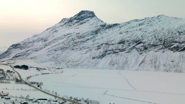 Aerial view of a serene winter landscape in Norway, showcasing the snow covered Geiranger Mountains and the frozen Eidsvatnet Lake.