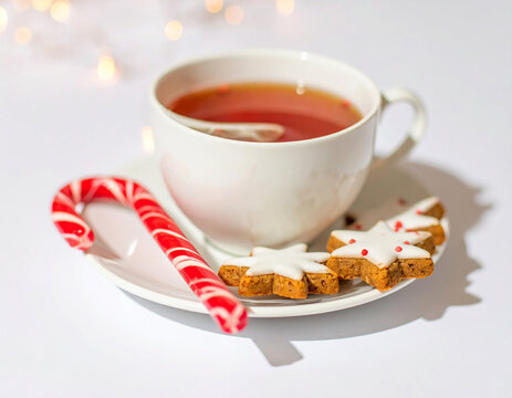 White teacup with candy cane and star shaped gingerbread cookies on a saucer