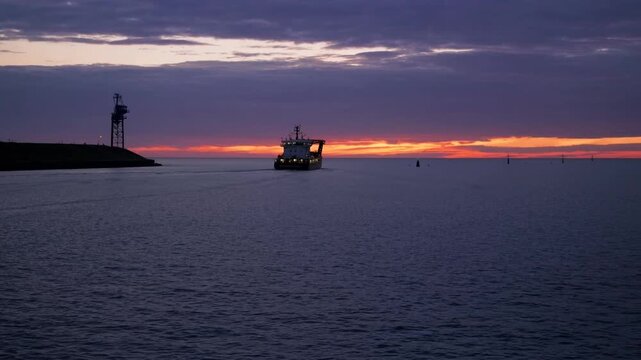 Offshore Service Vessel Departing from Harbor at Sunrise with Dramatic Sky