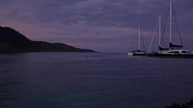 Scenic view of shoreline at dusk on Mediterranean isle featuring mountainous cove and boat harbor