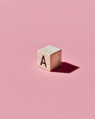 Single Wooden Alphabet Block A on Pastel Pink, Minimalist Learning Concept