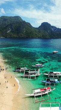 Tropical beach scene with boats and mountains in El Nido, Palawan, Philippines Picturesque tropical beach with boats and mountain backdrop in El Nido, Palawan, Philippines