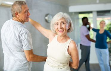 Obraz premium Group of multinational sports aged people rehearsing social dance in dance hall