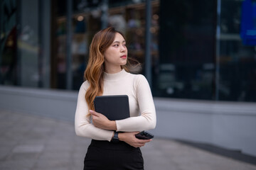 woman wearing a white sweater and black pants is holding a black book
