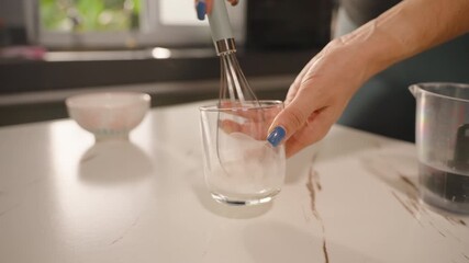 Close Up Whisk Stirring Mixture in Glass on White Kitchen Counter under Sunlight, Slow Motion, Baking Preparation Concept