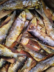 Close-up of traditional smoked fish stacked together, showcasing preserved seafood with a rustic and authentic texture. Perfect for illustrating local cuisine, food preservation methods,or traditional