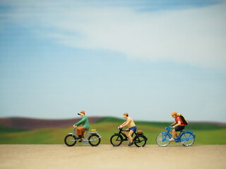 Naklejka premium Mini toy of action figure at outdoor with blurred background. Toy photography concept. A man with bicycle. Enjoying bicycle at morning.