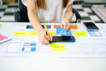 Creative UX UI designer working on app wireframe layout with sticky notes and color palette. web...
