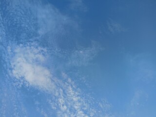 Beautiful morning sky with soft white clouds scattered on a bright blue background
