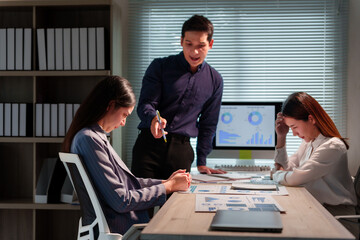Asian manager scolding two frustrated employees during a tense office meeting, highlighting stress and conflict in the workplace environment