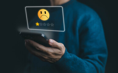 Customer holding smartphone showing poor service rating with sad emoji and one star review,...