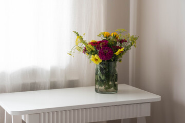 A beautiful display of colorful flowers in a glass vase, enhancing a bright and lovely interior ambiance
