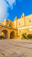 Fototapeta premium A sunlit courtyard with arched passageways and a large, imposing stone building