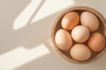 Wooden bowl with six eggs, assorted sizes and colors, on white surface with light background, shadows and contrast.