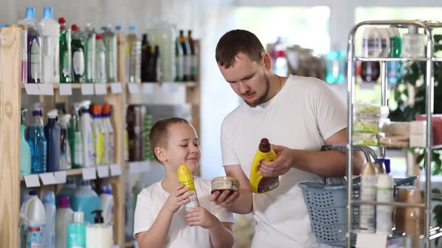 Young man with his son buyers choosing parquet and wood cleaner in household chemicals store