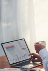 Vertical Horizon Portrait Asian Businessman typing laptop computer drinking coffee cup at office desk via wireless internet working online. Vertical Asian handsome man Freelance business person