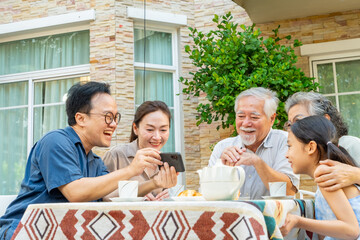 Happy Asian three generation family using mobile phone watching movie, online shopping, social...