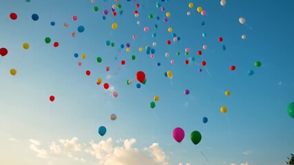 Colorful balloons rising into blue sky