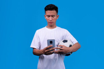 Worried Soccer Fan Holding Ball And Checks Smartphone With Serious Expression