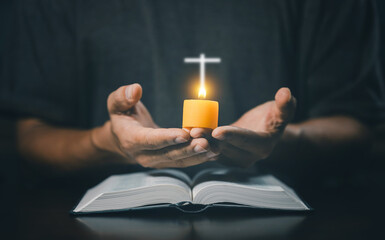Christian man worship. Hands folded in prayer on a Holy Bible in home concept for faith. Spirituality and religion. Man praying on holy bible with candle light. Man hand with Bible praying.