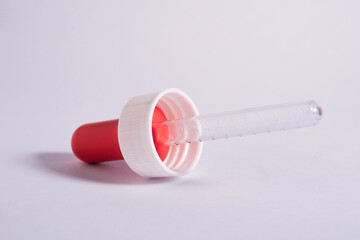 One piece of pipette with red lid isolated on horizontal plain background.
