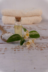 Vertical shot of a white wooden spa table with flowers, relaxing oil, and salts