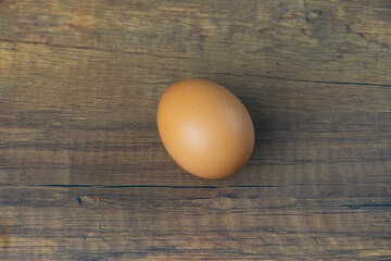 Light brown shelled chicken eggs lay on a wooden floor.