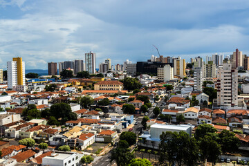 Naklejka premium Marilia, SP, Brazil, February 13, 2025. Panoramic view of a Marilia city showcasing diverse architecture, combining modern buildings and traditional houses under a cloudy sky.