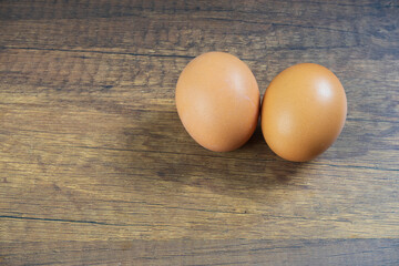 Light brown shelled chicken eggs lay on a wooden floor.