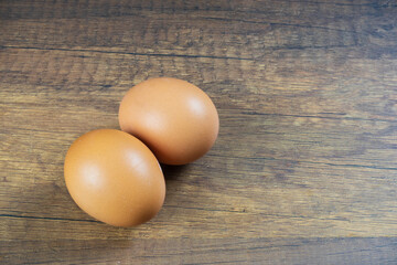 Light brown shelled chicken eggs lay on a wooden floor.