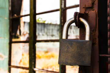 Padlock on an old window in Brazil. Symbol of security contrasting with decay. Rust and peeling paint tell a story of time and abandonment.