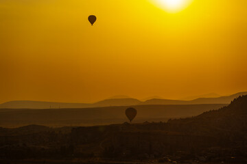 Fototapeta premium Hot air balloon flying over rocky landscape at sunrise in Cappadocia. Turkey
