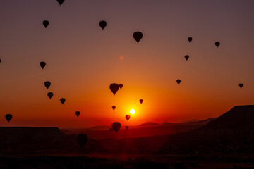 Hot air balloon flying over rocky landscape at sunrise in Cappadocia. Turkey