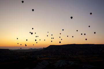 Hot air balloon flying over rocky landscape at sunrise in Cappadocia. Turkey