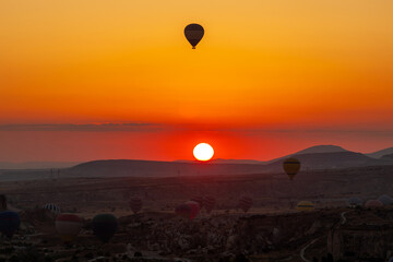 Hot air balloon flying over rocky landscape at sunrise in Cappadocia. Turkey