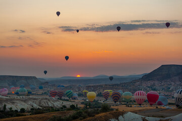 Hot air balloon flying over rocky landscape at sunrise in Cappadocia. Turkey