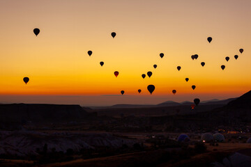 Hot air balloon flying over rocky landscape at sunrise in Cappadocia. Turkey