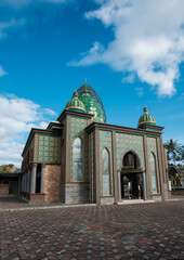 Majestic Islamic Mosque with Ornate Green and Gold Geometric Patterns and Domes against Blue Sky