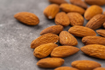 Pealed almond nuts on the gray concrete background. Healthy food. Selective focus.