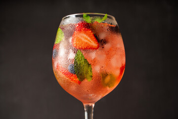 Fresh summer cocktail with strawberry and blueberry in wineglass. Strawberry soda drink on the...