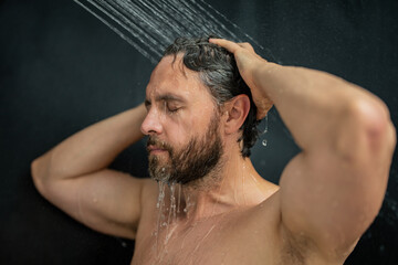 Hispanic man washing hair in bathroom. Guy bathing shower head in bathtub. Male face in shower. Man...