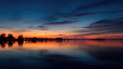 Fototapeta premium A spectacular sunset with gradient orange and purple clouds and a cityscape in the distance creates a panoramic abstract skyscape.
