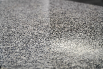 A mottled grey surface, with varied tones and textures. The fine granules create a uniform...