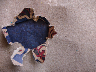 Hole in the paper. Torn hole in brown paper with black empty background. Copy space, mockup. Place...