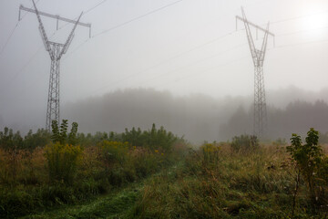 View of high-voltage power line supports during heavy morning fog