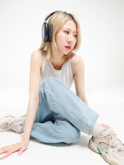 Asian fashion portrait young beautiful cheerful cute woman, blonde short hair wearing headphones...